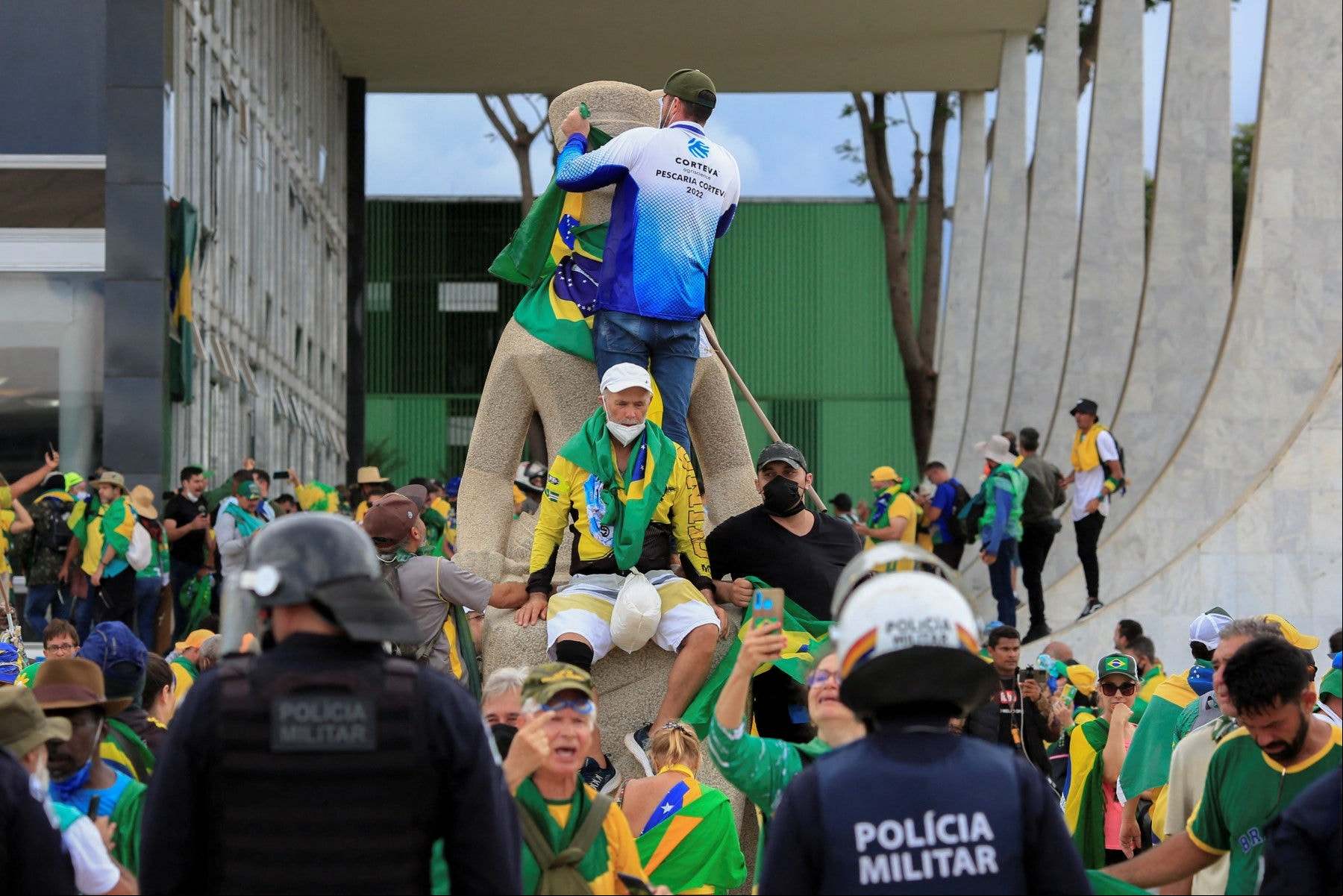 Apoiadores de Jair Bolsonaro tomam a Praça dos Três Poderes e sobem, na estátua da Justiça, diante de policiais militares, em 8 de janeiro de 2023