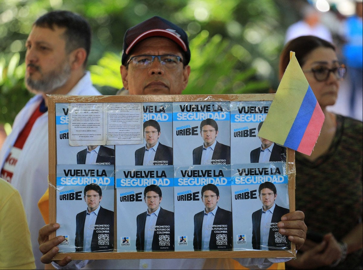 A man holds a sign with propaganda for presidential candidate Miguel Uribe during a protest against violence and in favor of peace in Medellin, Colombia, on June 8, 2025, the day after the attack on Uribe. A prominent Colombian right-wing presidential candidate who was shot during a campaign event in Bogota has successfully undergone initial surgery, the city's mayor said Sunday. Thirty-nine-year-old Senator Miguel Uribe was speaking to ers in the capital when a gunman shot him twice in the head and once in the knee before being detained. (Photo by JAIME SALDARRIAGA / AFP)